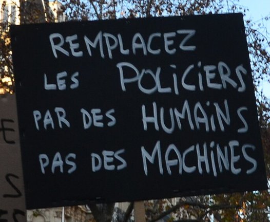 Pancarte « REMPLACEZ LES POLICIERS PAR DES HUMAINS PAS DES MACHINES », Paris (75), 28 novembre 2020